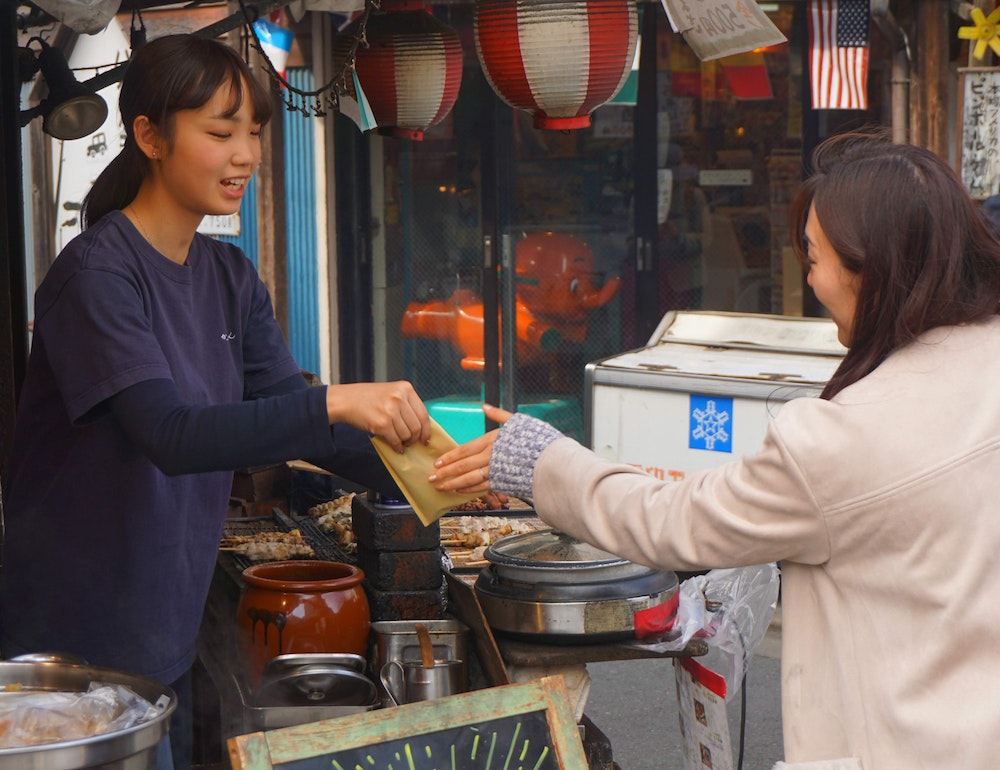 Woman buying food from a street vendor.